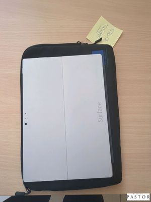 un ordinateur portable posé sur un bureau, à côté d'un bloc-notes