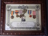 une vieille photo représentant un tableau encadré sur lequel figurent des médailles militaires et des décorations