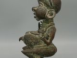 an old bronze figurine of a woman sitting on a rock