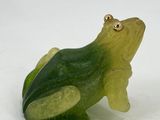 a green and yellow frog figurine sitting on a white surface