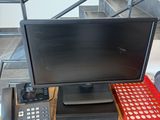 a desk with a computer, keyboard, phone, and other items on it
