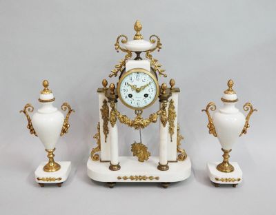a white and gold clock and three white vases