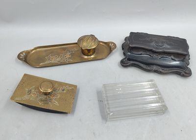 trois objets en laiton et en verre sont posés sur une surface blanche