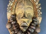 an image of a wooden mask with shells around it