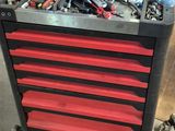une boîte à outils rouge contenant des outils, dans un garage