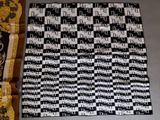 a black and white quilt on the floor next to a chair