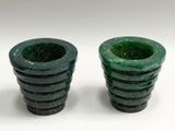 two green vases sitting next to each other on a white surface