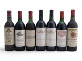six bottles of wine are lined up in a row on a white surface
