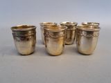 four silver cups are lined up in a row on a table