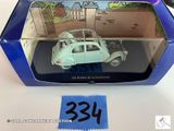 une petite voiture miniature dans une boîte bleue posée sur une table