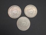 three silver coins sitting on top of a black surface