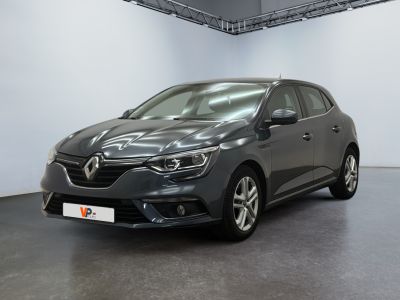 La voiture grise est garée dans une grande pièce aux murs blancs.