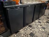 un réfrigérateur noir posé sur un sol carrelé dans une cuisine