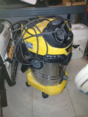 un aspirateur jaune et noir posé sur un sol carrelé