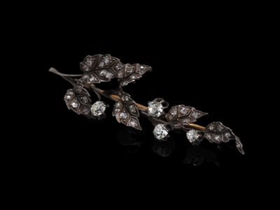 un gros plan sur une broche antique en forme de feuille sertie de diamants