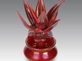un vase en verre rouge contenant une fleur rouge