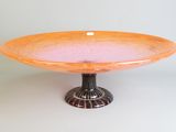 un bol en verre orange posé sur un socle en métal noir