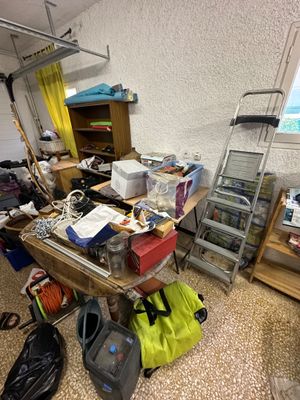 a cluttered room with a ladder and a window