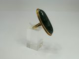 une image représentant une bague sertie d'une pierre verte sur un support transparent
