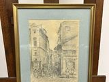 dessin représentant une scène de rue, encadré et posé sur un chevalet en bois