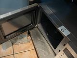 a microwave that is in the corner of a kitchen