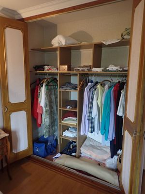 une photo d'une chambre avec une armoire remplie de vêtements