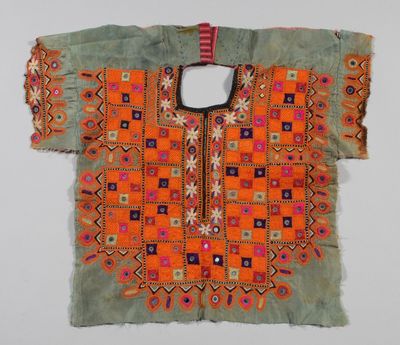une chemise brodée orange et verte, avec des motifs géométriques sur fond blanc