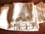 three white linen napkins with embroidered monograms on them on a couch