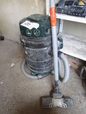 un aspirateur posé par terre à côté d'une étagère