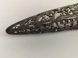 a close up of a silver broochle on a white surface