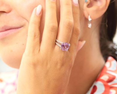 quelqu'un enfile à son doigt une bague sertie d'une pierre violette