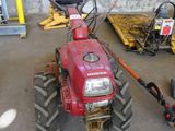 a red tractor parked in a garage next to other vehicles