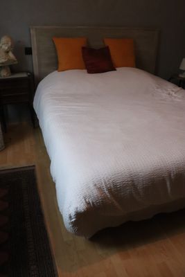 a white bed with orange pillows in a small room