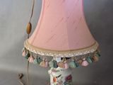 une lampe posée sur une table, avec un abat-jour rose