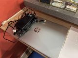 un ordinateur portable posé sur un bureau, avec un chargeur branché dessus