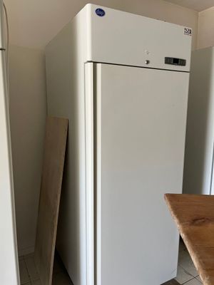 white refrigerator freezer sitting in a kitchen next to a wooden table