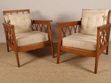 une paire de chaises de style « mid-century » avec des coussins beiges, posées sur un sol recouvert de moquette