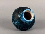 a blue and black vase sitting on a gray surface