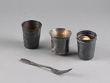 three cups and a spoon sitting next to each other