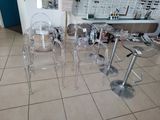 two clear chairs and a table in the middle of a room
