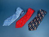 three ties with different designs on them on a blue surface
