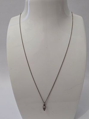 un mannequin blanc portant un collier orné d'un crâne