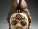 a close up of a wooden mask with a bird on top of it