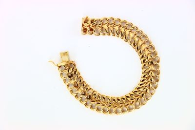 gros plan d'un bracelet en chaîne en or sur une surface blanche