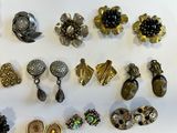 many different types of brooches and earrings on the table