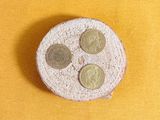 three coins sitting on top of a cake on a yellow surface