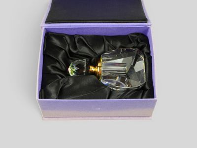 une image représentant un flacon de parfum en verre dans une boîte violette