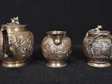 three silver vases sitting next to each other on a black surface
