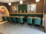 tables and chairs in a restaurant with a large painting on the wall
