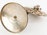a silver object with a bird on it on a white surface